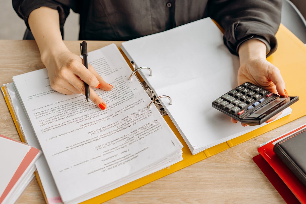 about-us A woman reviewing documents and using a calculator on a wooden table.